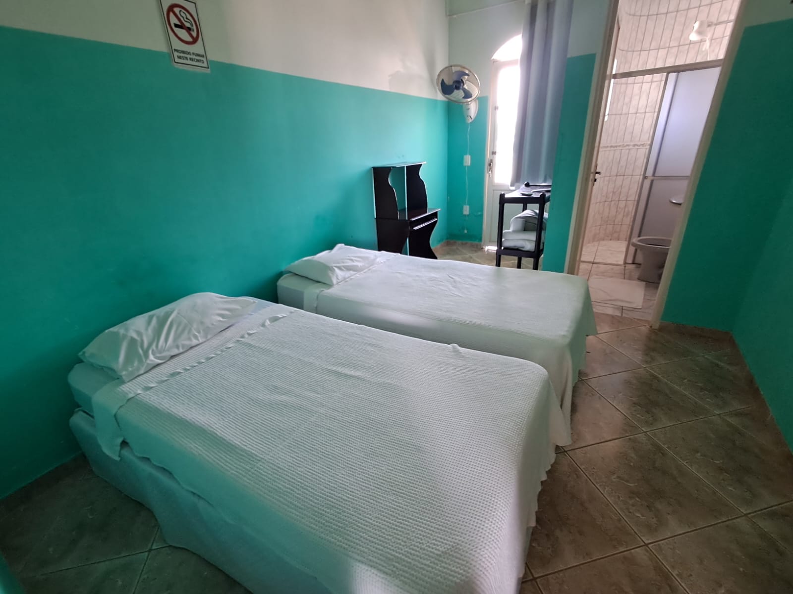 Quarto azul com duas camas de solteiro e porta do banheiro